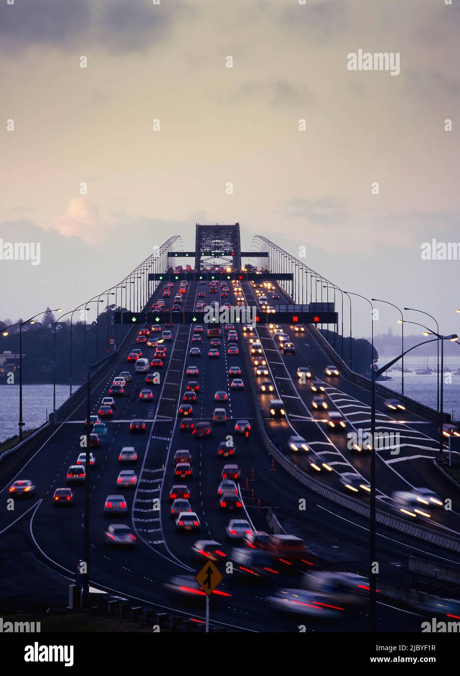 Traffico che scorre in entrambi i sensi sul Ponte del Porto di Auckland al crepuscolo Foto Stock