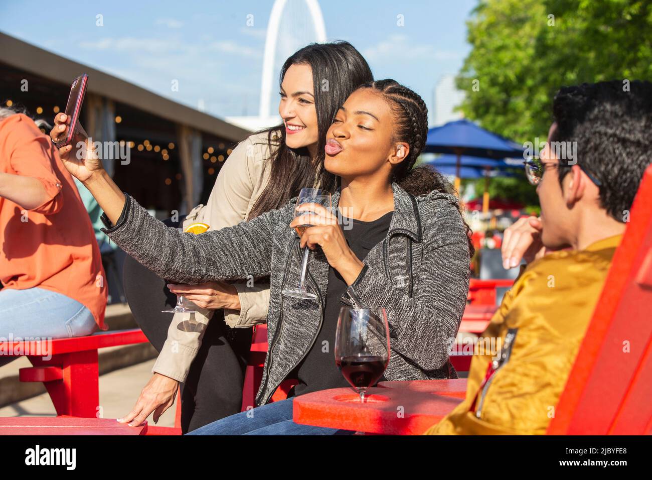 Gruppo di giovani collaboratori che si affacciano sul patio all'aperto con bevande per l'happy hour, due ragazze che prendono selfie con telefono cellulare Foto Stock
