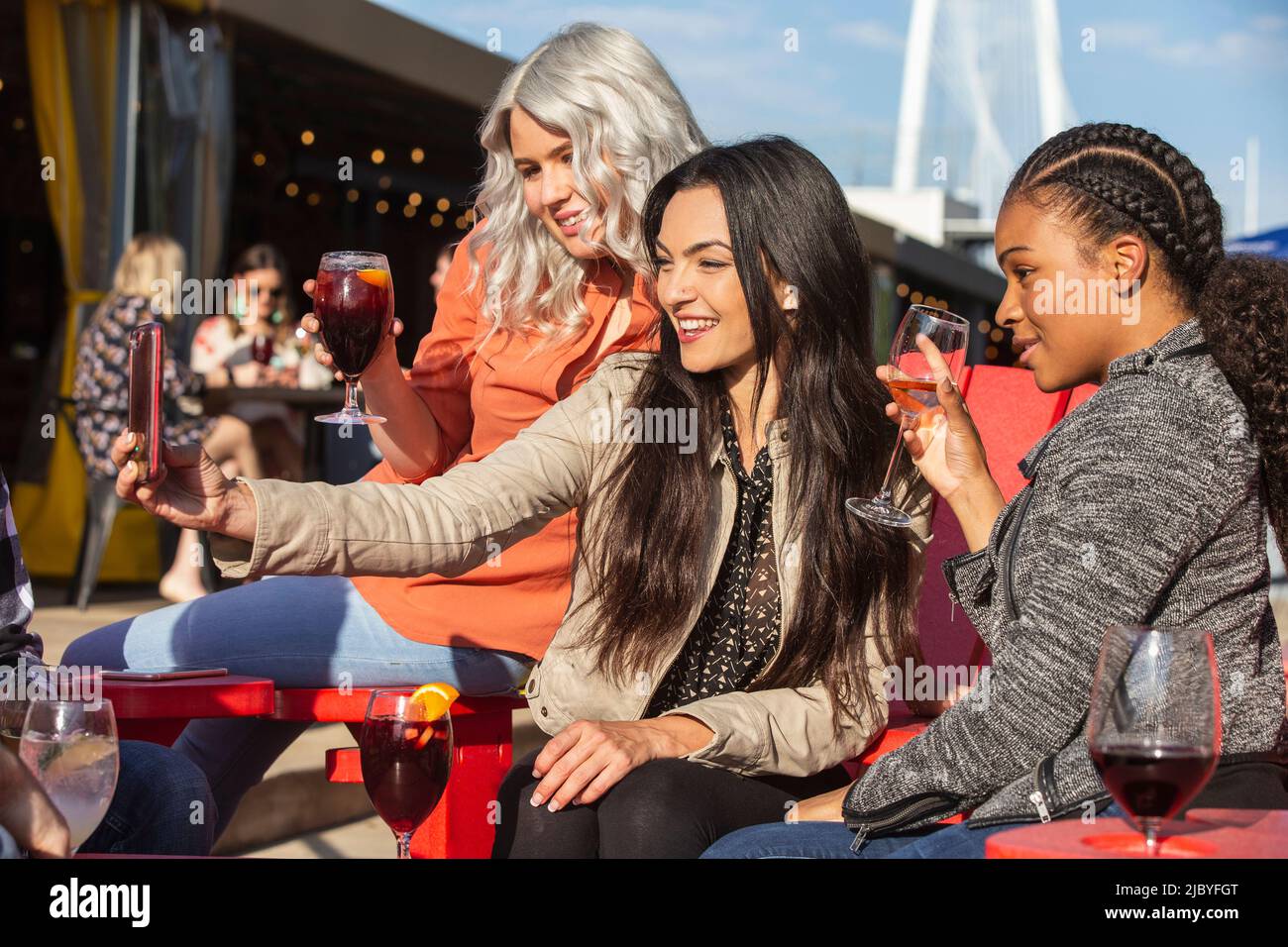 Gruppo di giovani collaboratori che si affacciano sul patio all'aperto con bevande per l'happy hour, donne che prendono selfie con telefono cellulare Foto Stock