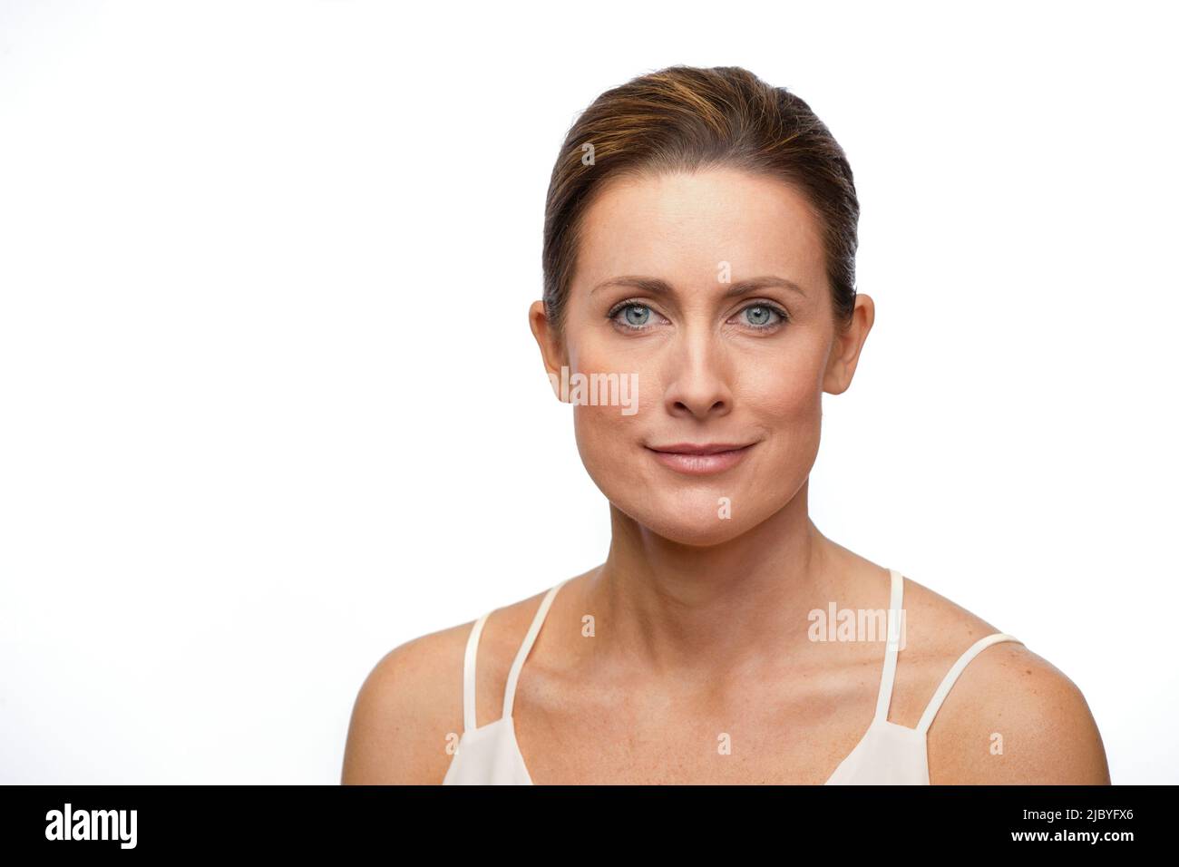 Ritratto di donna bianca di mezza età con capelli marroni tirati indietro, guardando la fotocamera con un lieve sorriso Foto Stock
