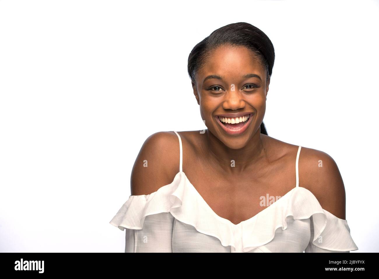 Ritratto di giovane donna nera con capelli tirati indietro guardando la macchina fotografica con un sorriso Foto Stock