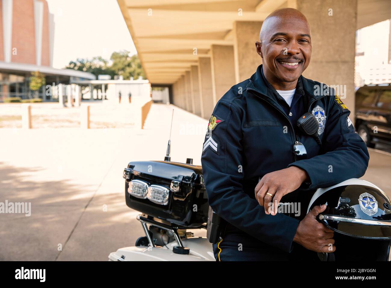 Ritratto di ufficiale di polizia seduto sul suo motociclo esterno guardando verso la macchina fotografica sorridente Foto Stock
