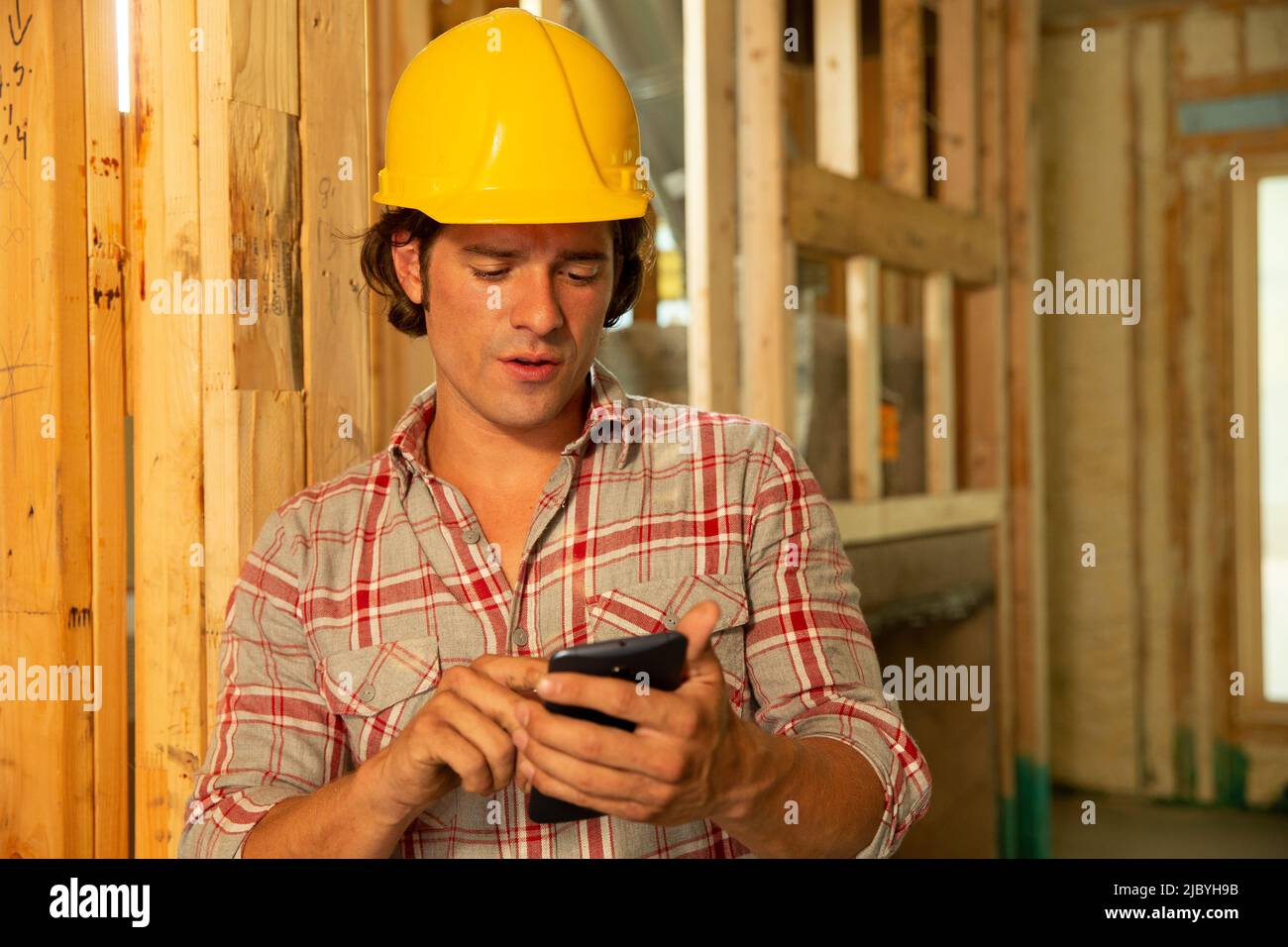 Lavoratori edili che indossano un elmetto sul cantiere utilizzando il telefono cellulare Foto Stock