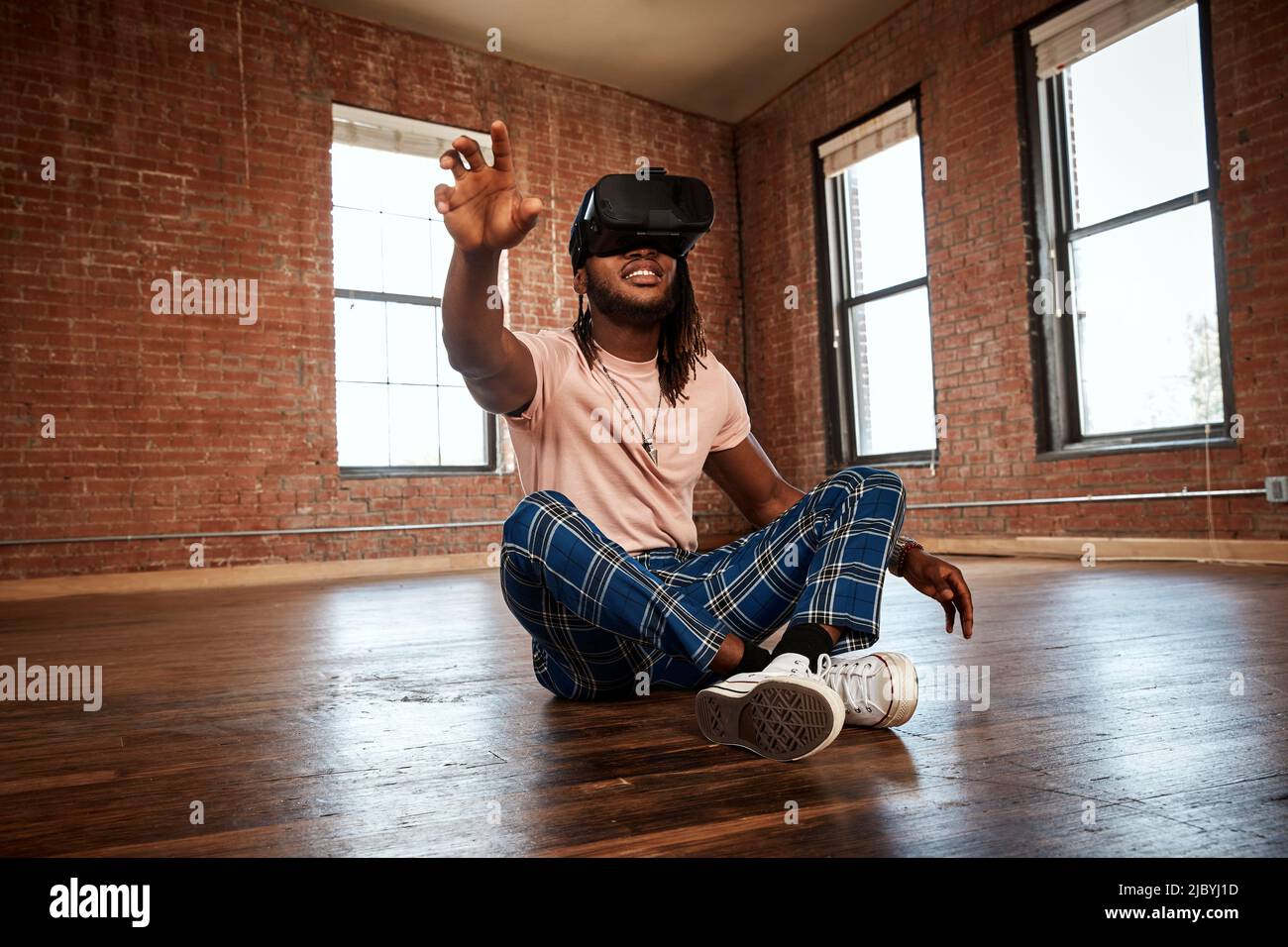 Ritratto di un giovane etnia elegante che indossa un visore VR in uno spazio vuoto Foto Stock