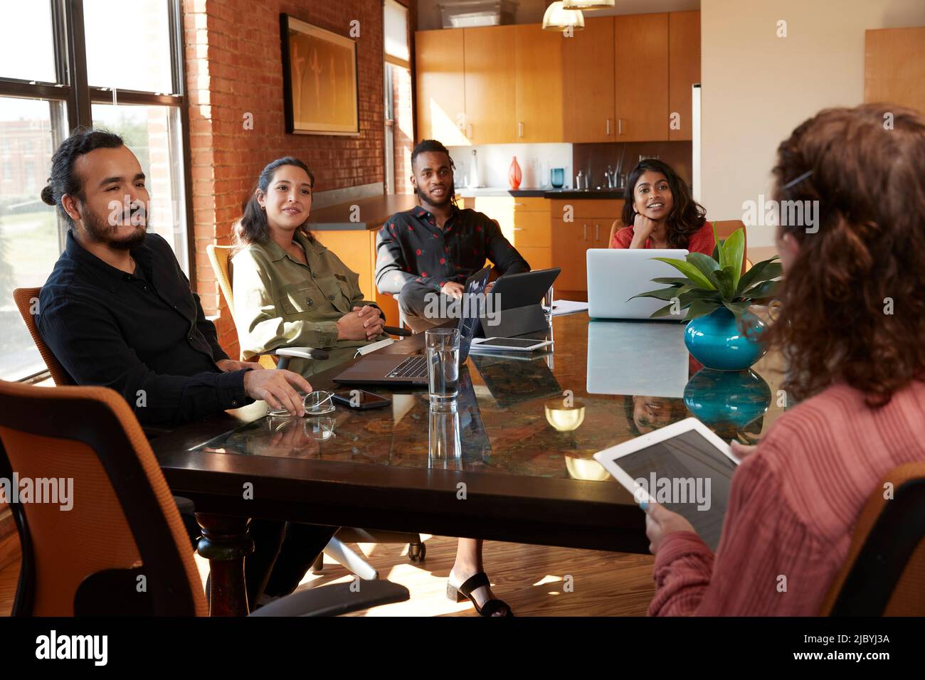 gruppo di colleghi seduti a un grande tavolo per conferenze con i loro dispositivi in discussione Foto Stock