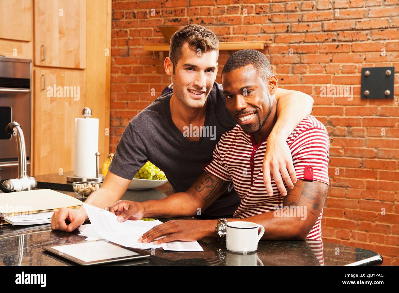 Coppia gay che guarda la documentazione in cucina Foto Stock