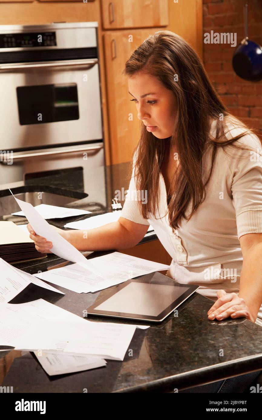 Donna ispanica che guarda il lavoro di ufficio in cucina Foto Stock