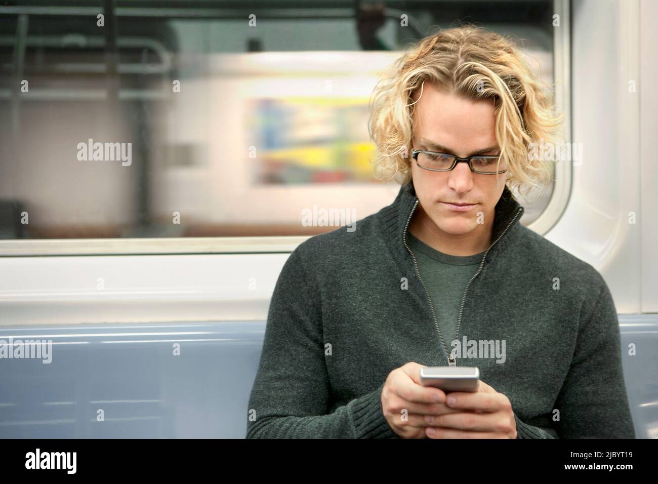 Uomo caucasico la messaggistica di testo sul telefono cellulare sul treno della metropolitana Foto Stock