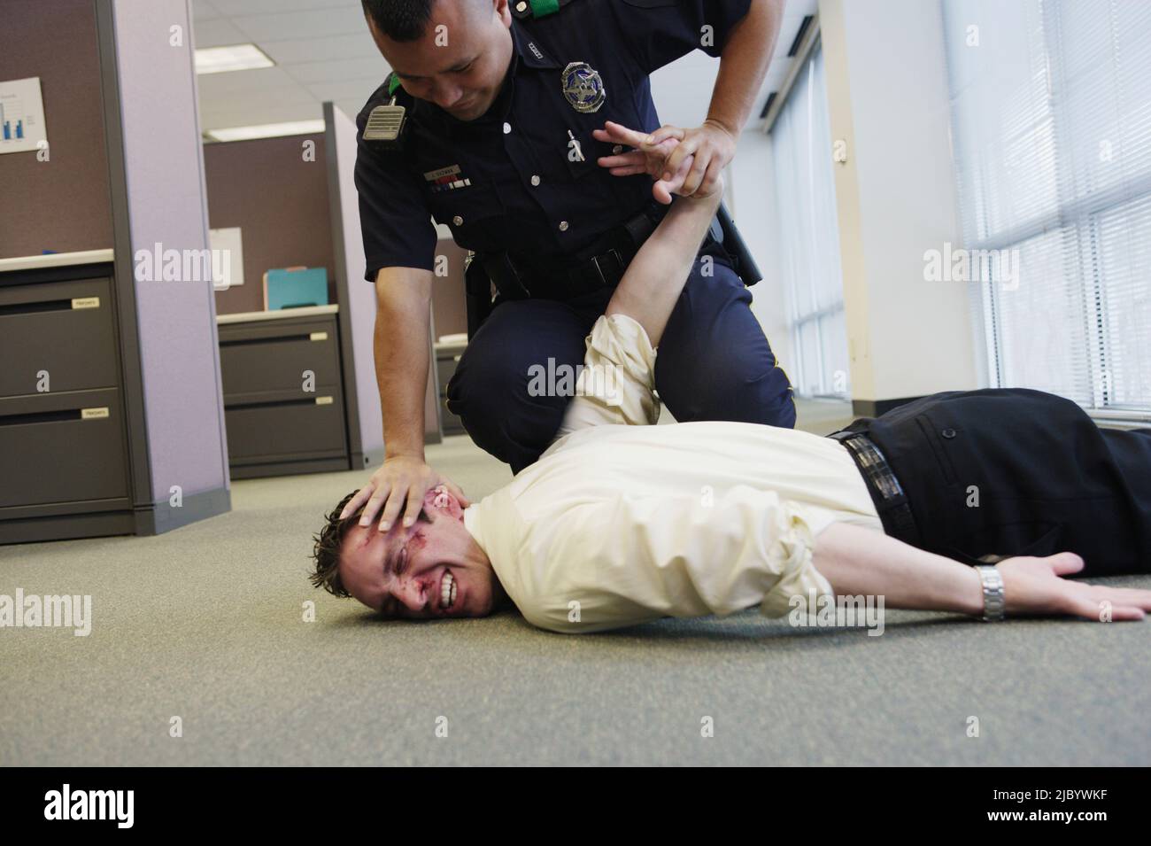 Funzionario di polizia holding battuto l uomo d affari sul pavimento in office Foto Stock