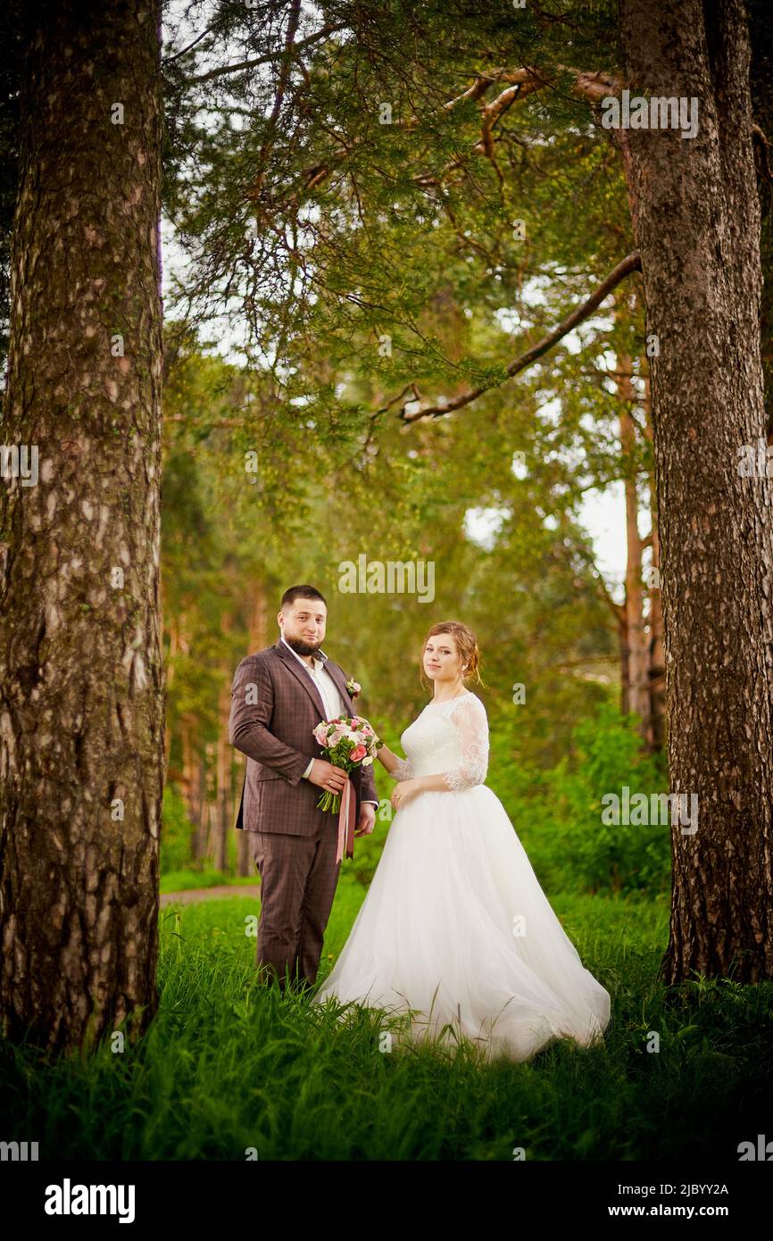 Concetto di matrimonio. Sposi e sposi nel parco verde in una giornata estiva Foto Stock