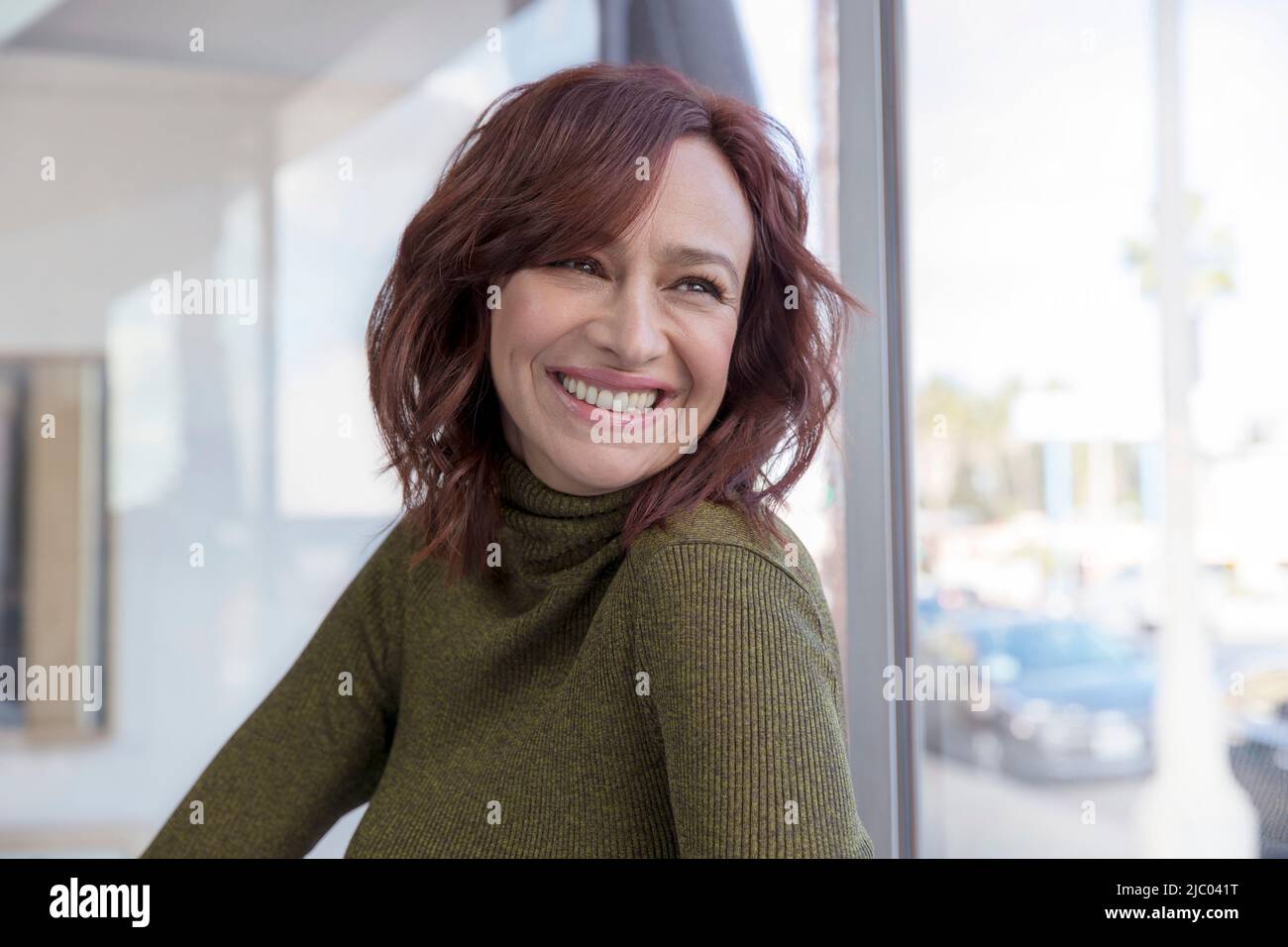 Una giovane donna di mezza età guarda indietro sulla spalla sorridendo. Foto Stock