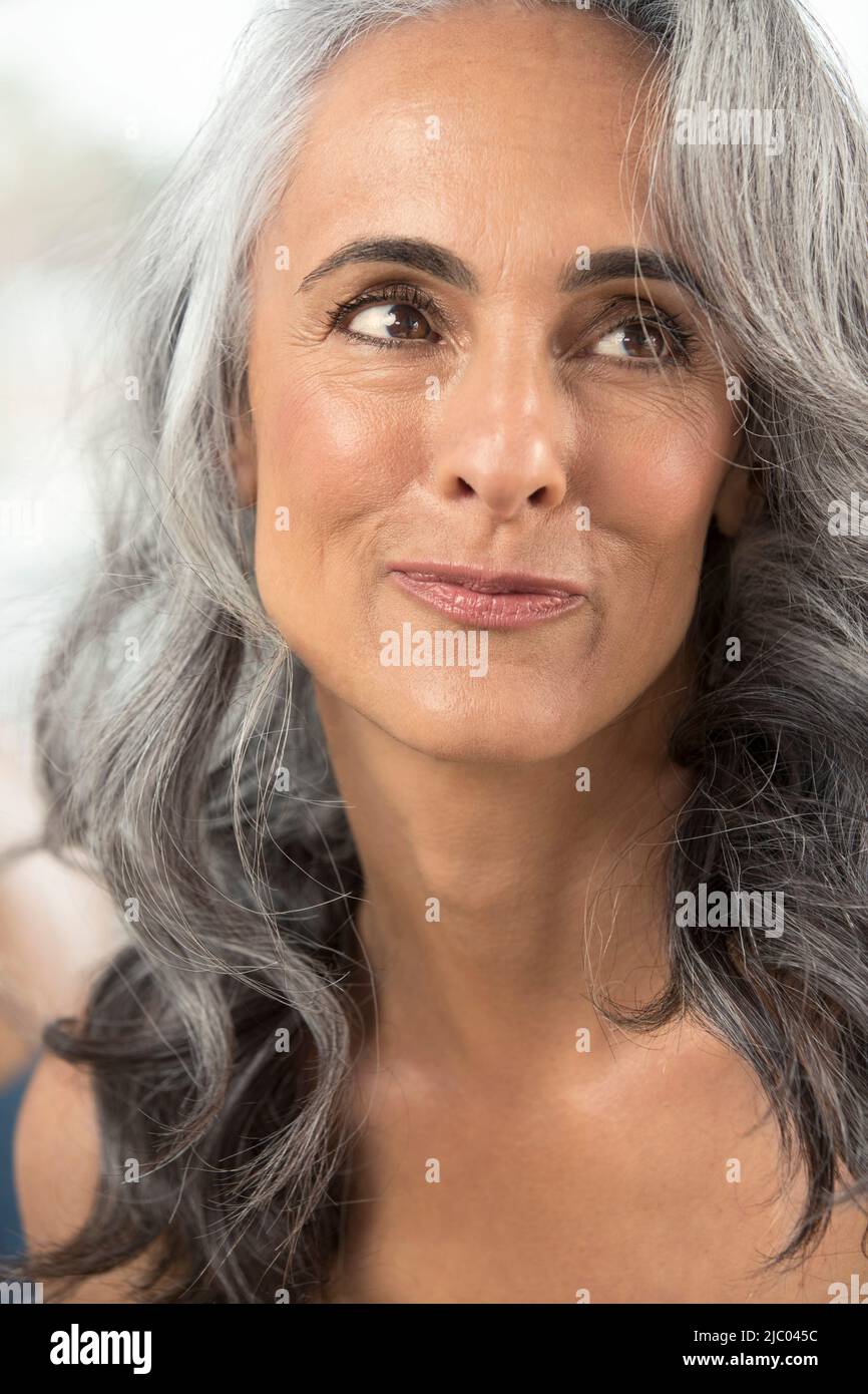 Donna di mezza età con capelli grigi guarda fuori dalla fotocamera. Foto Stock