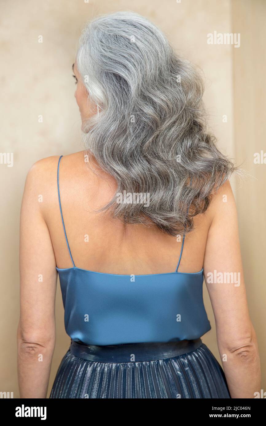 Primo piano medio di una donna di mezza età con capelli grigi allontanati dalla fotocamera. Foto Stock