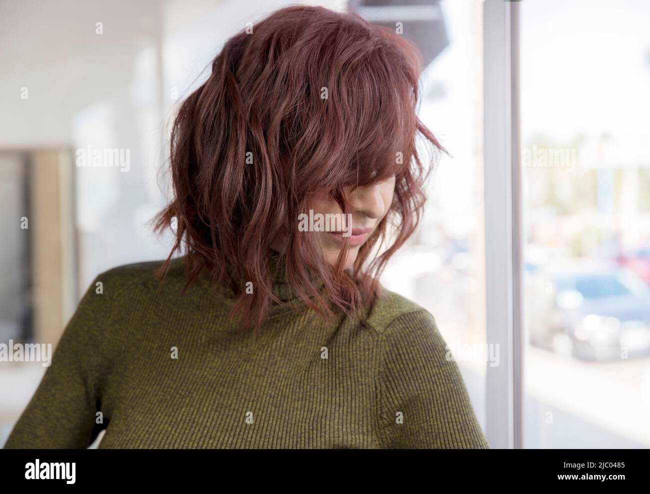 La donna di mezza età con testa rossa guarda giù coprendo il suo viso con i suoi capelli. Foto Stock