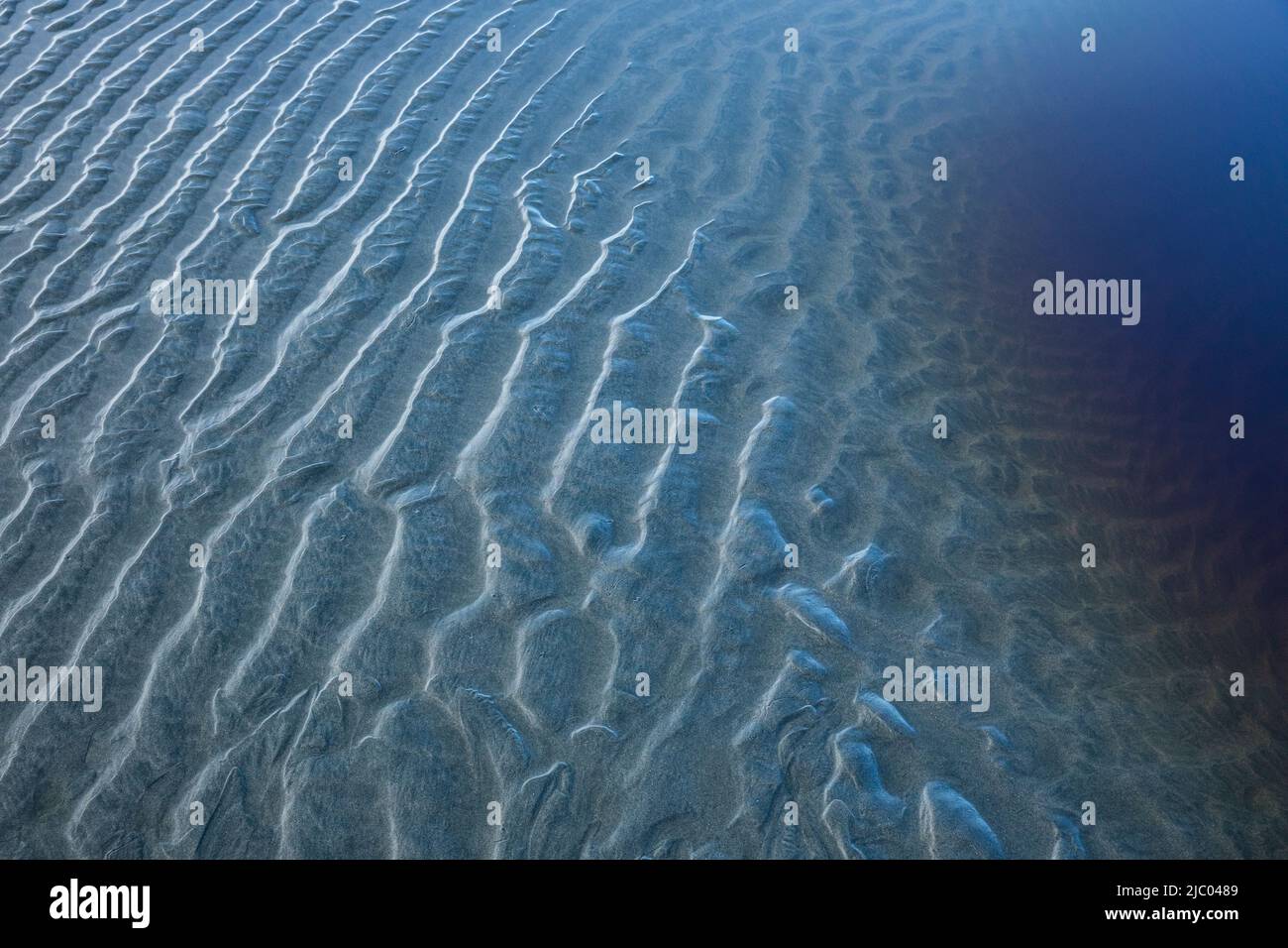 Motivi di sabbia e una piscina d'acqua con tannini in esso a bassa marea su Tonquin Beach vicino Tofino, BC, Canada. Foto Stock