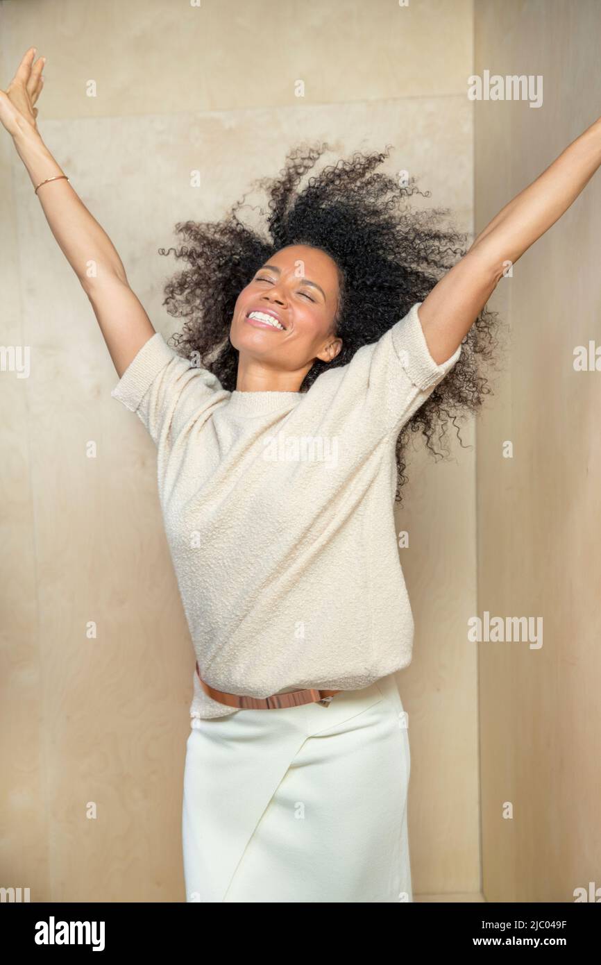 Una donna di mezza età con le mani in aria e testa inclinata all'indietro ridendo. Foto Stock