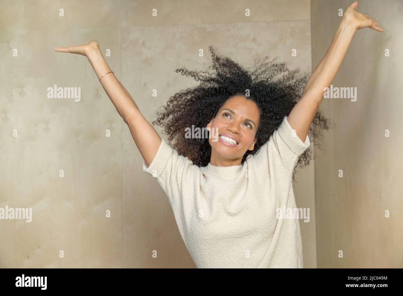 Ritratto orizzontale di una donna da corsa mista con le mani in capelli, ridendo. Foto Stock