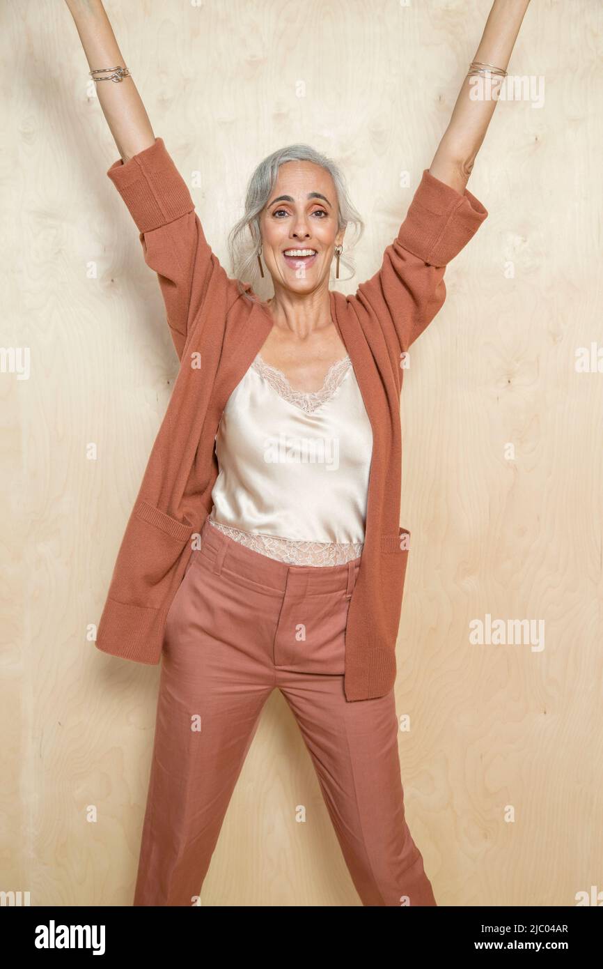 Una donna di mezza età con capelli grigi sorridenti con le mani in su. Foto Stock