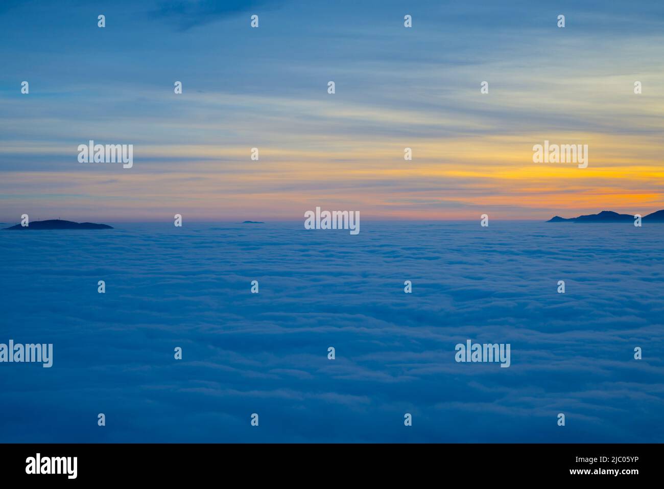 Vista aerea sulla montagna innevata sopra il paesaggio nuvoloso a Dusk a Locarno, Svizzera. Foto Stock