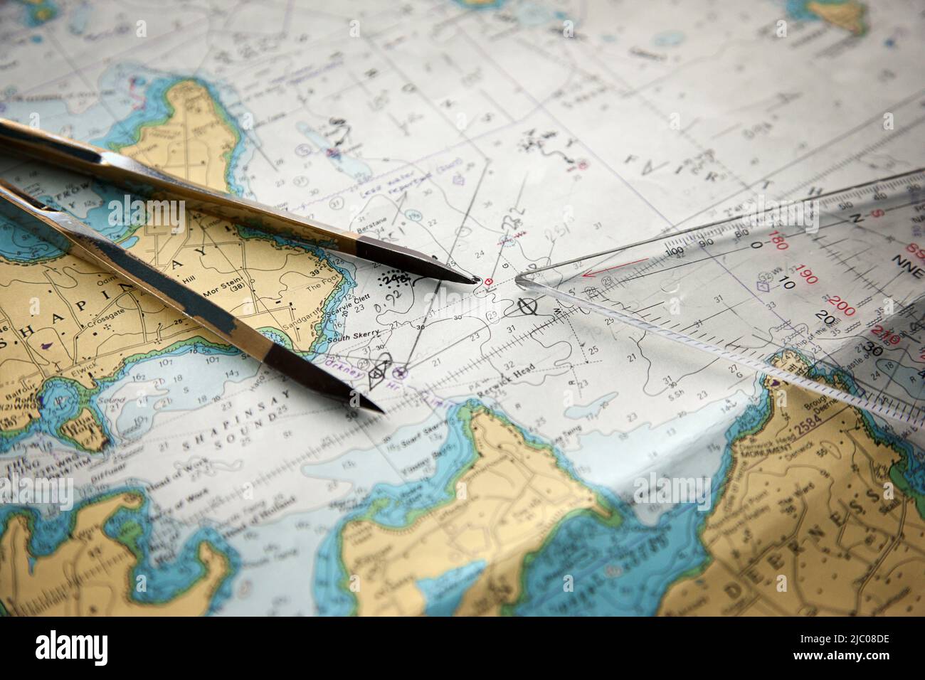 Bussola e righello poggiano su una mappa dell'isola di Shapinsay e della Penisola di Deerness delle Isole Orkney al largo della costa della Scozia Foto Stock