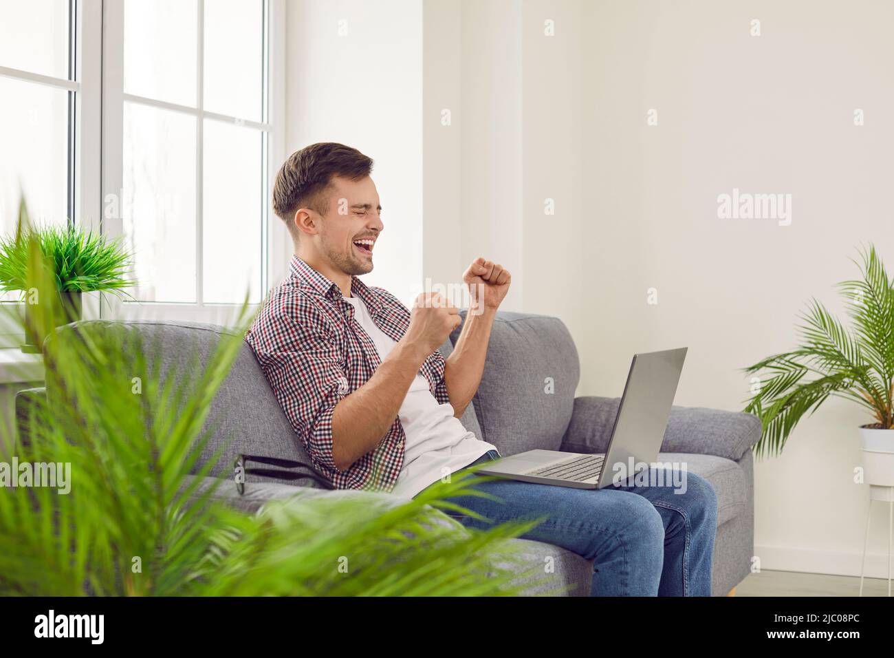 Gioiosa ragazzo eccitato con laptop gioisce in successo, vittoria, buon profitto o nuovo lavoro. Foto Stock