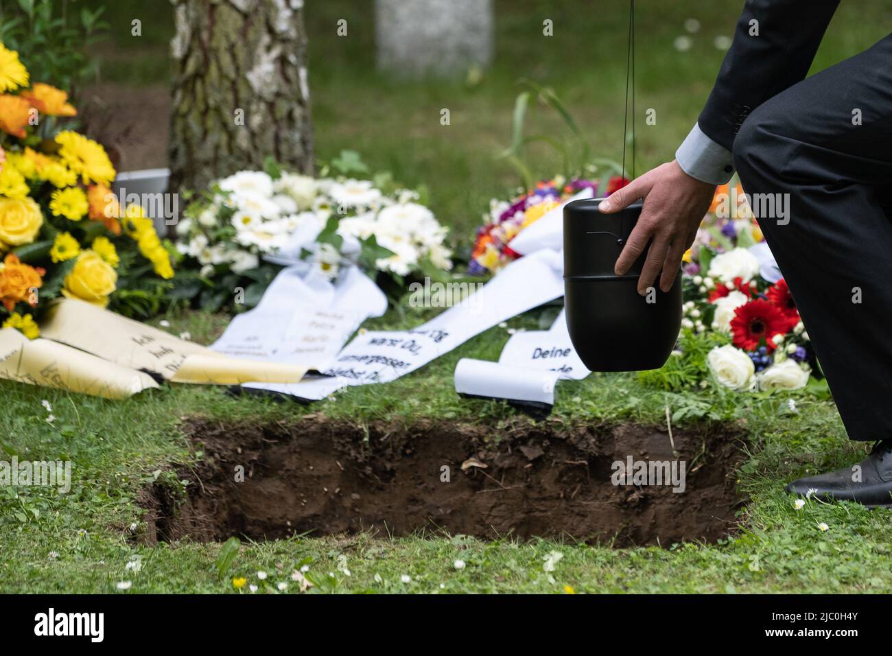 PRODUZIONE - 04 giugno 2022, bassa Sassonia, Göttingen: Un fratello Tobias abbassa un'urna in una tomba durante una sepoltura comunitaria della fratellanza Tobias. La Fratellanza Tobias di Göttingen seppellisce persone senza familiari. (A dpa-KORR 'compagni di viaggio finale') Foto: Swen Pförtner/dpa Foto Stock