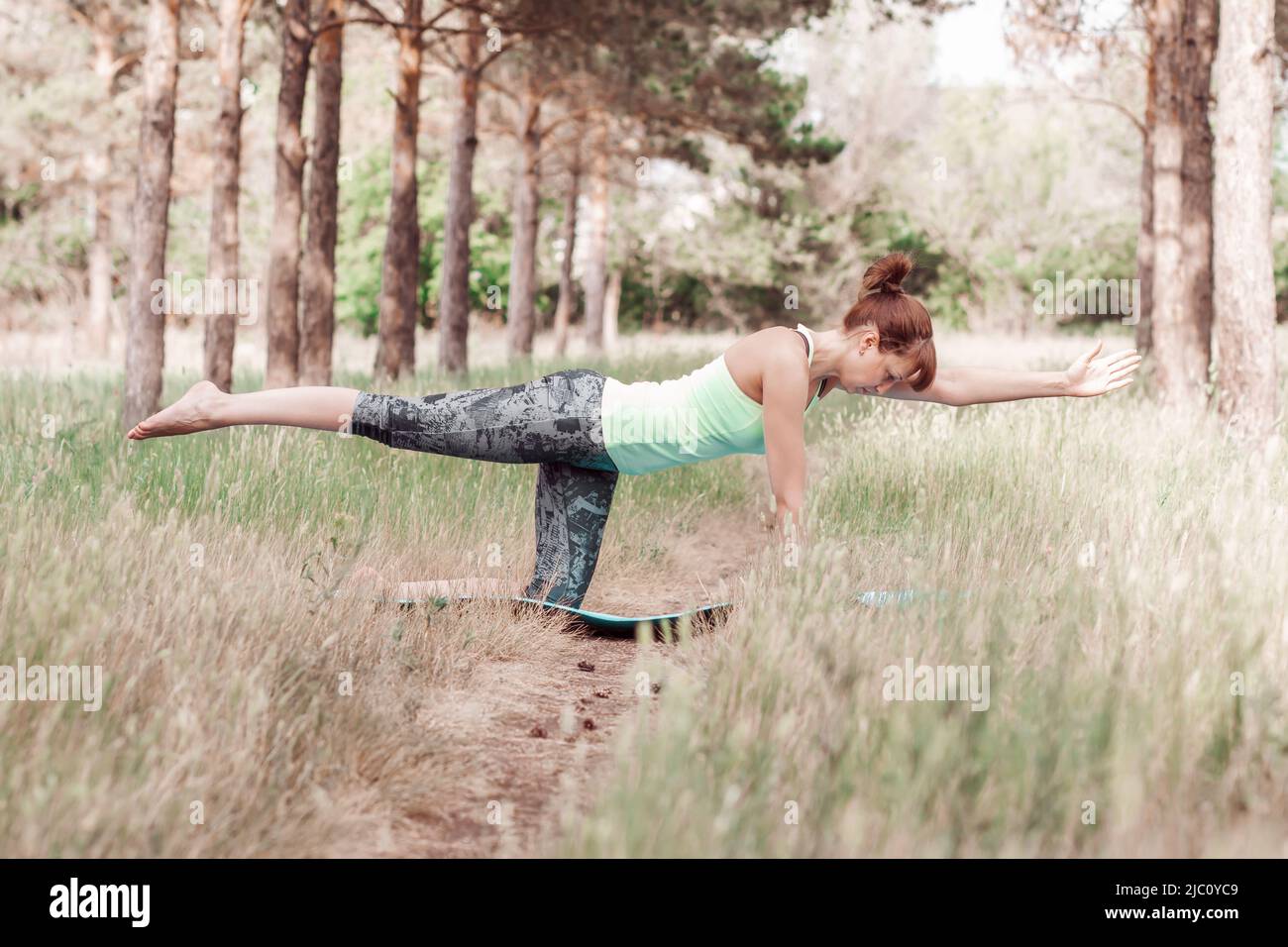 Giovane donna slim in abbigliamento sportivo che pratica yoga e meditazione in natura per il sollievo dallo stress e la mente sana Foto Stock