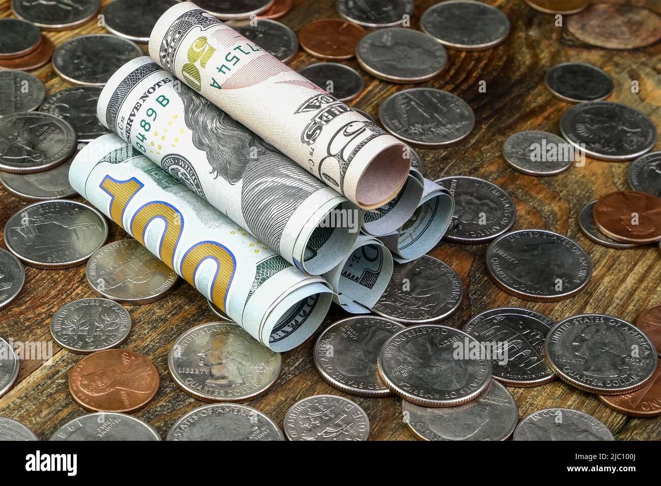 Banconote in dollari americani arrotolate in tubo e monete statunitensi. Cassa e risparmio di attività finanziarie e di finanziamenti per la casa durante la crisi economica. Primo piano. Foto Stock