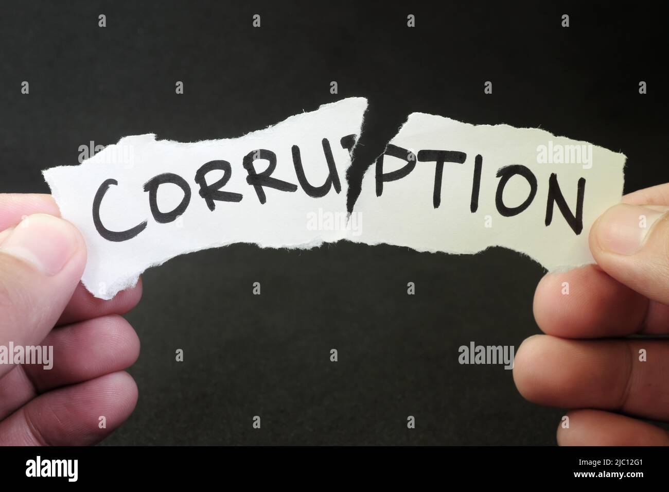 Stop e combattere il concetto di corruzione. La mano umana strappa un pezzo di carta con la parola scritta corruzione. Foto Stock