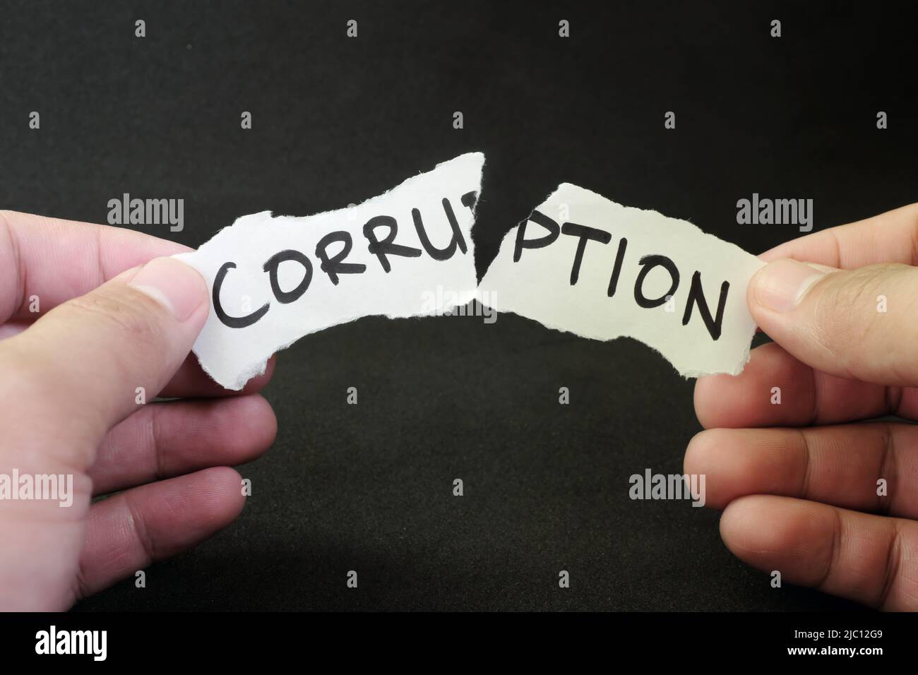 Stop e combattere il concetto di corruzione. La mano umana strappa un pezzo di carta con la parola scritta corruzione. Foto Stock