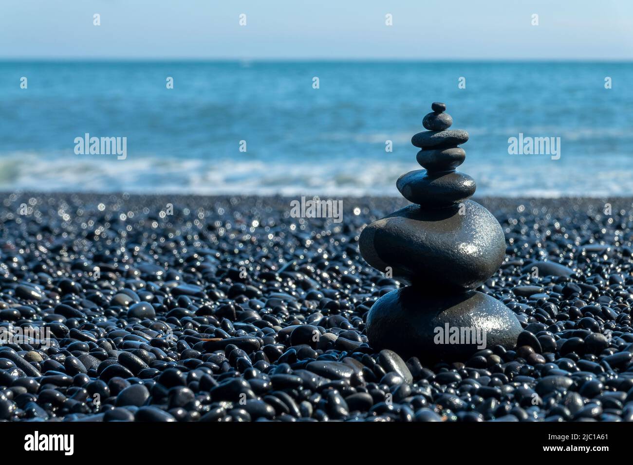Pietre equilibrate sulla spiaggia nera di Reynisfjara in Islanda Foto Stock