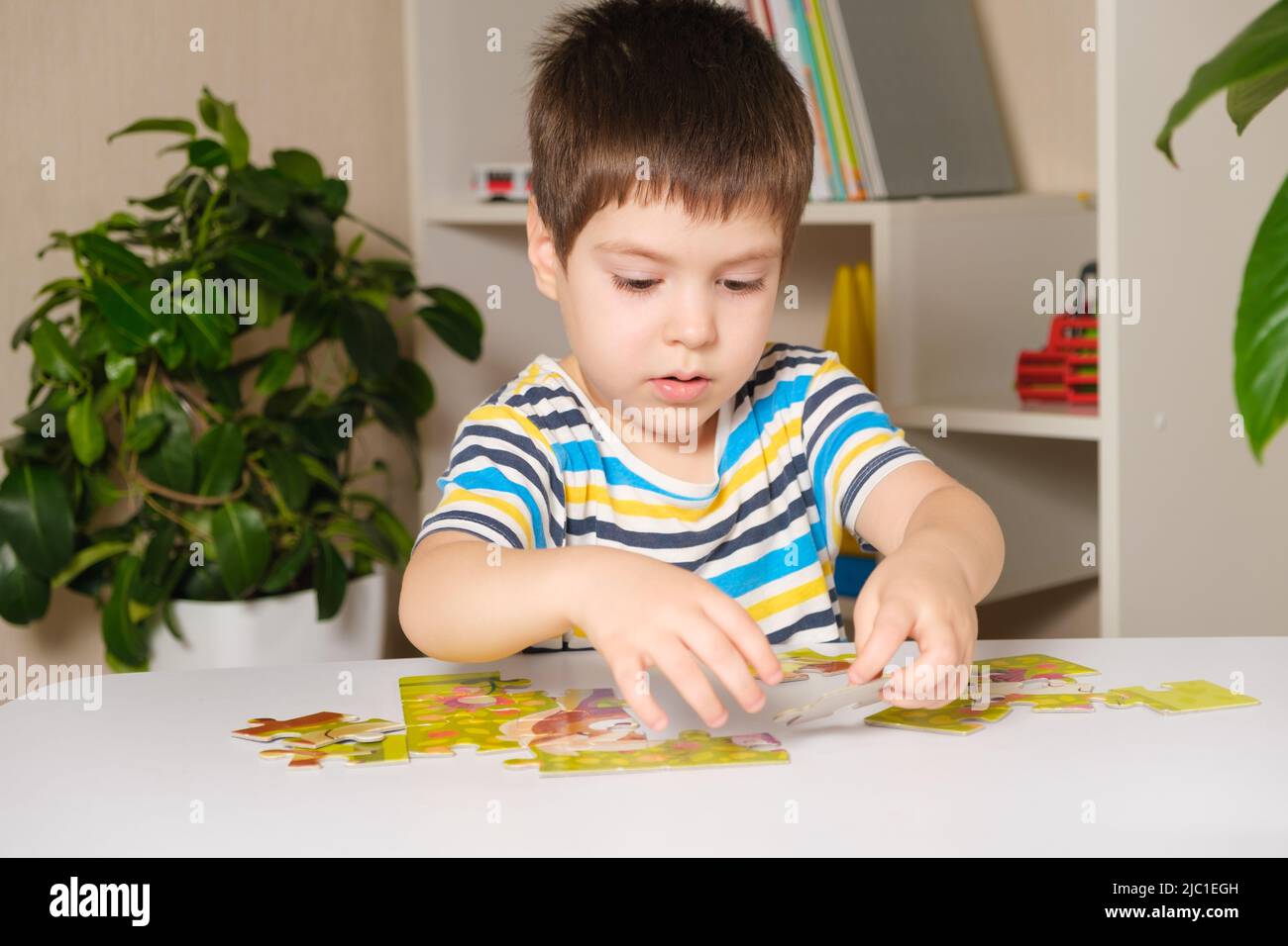 Un preschooler suona puzzle, mette insieme un'immagine Foto Stock