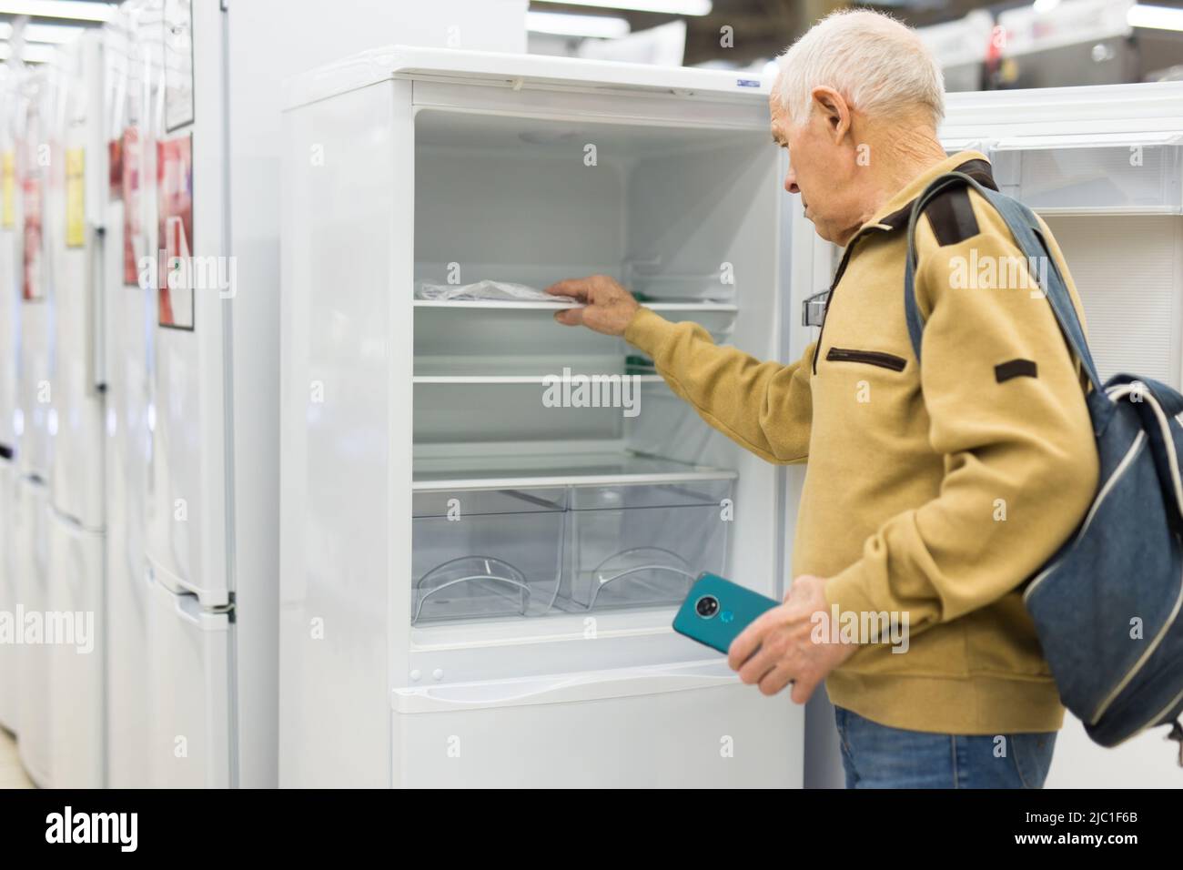 senor uomo pensionato acquistare frigorifero in showroom di elettrodomestici negozio Foto Stock