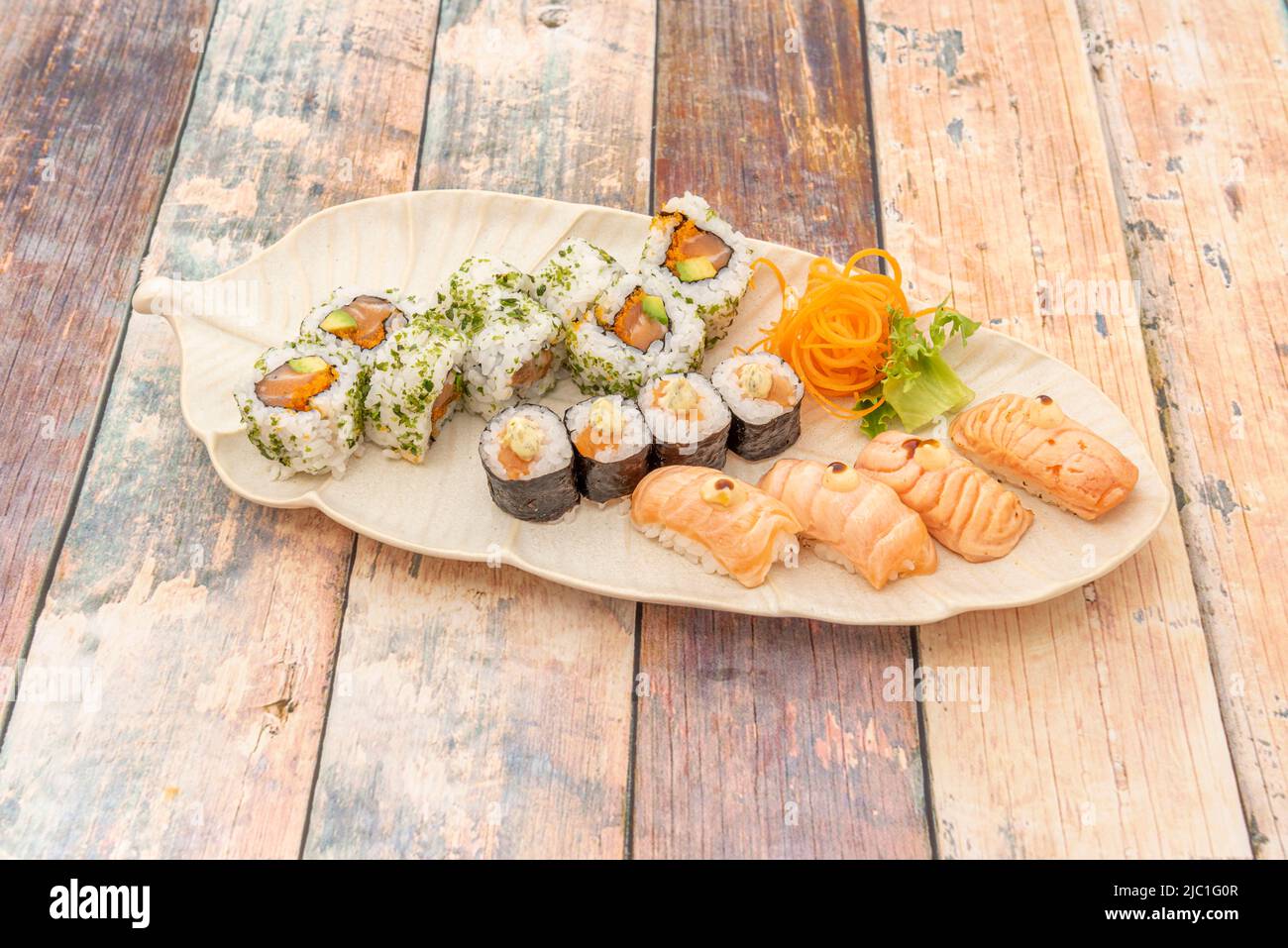 Vassoio di sushi misto con maki di riso con salmone norvegese, nigiris con flambé di salmone e uramaki con salmone e avocado e prezzemolo tritato Foto Stock
