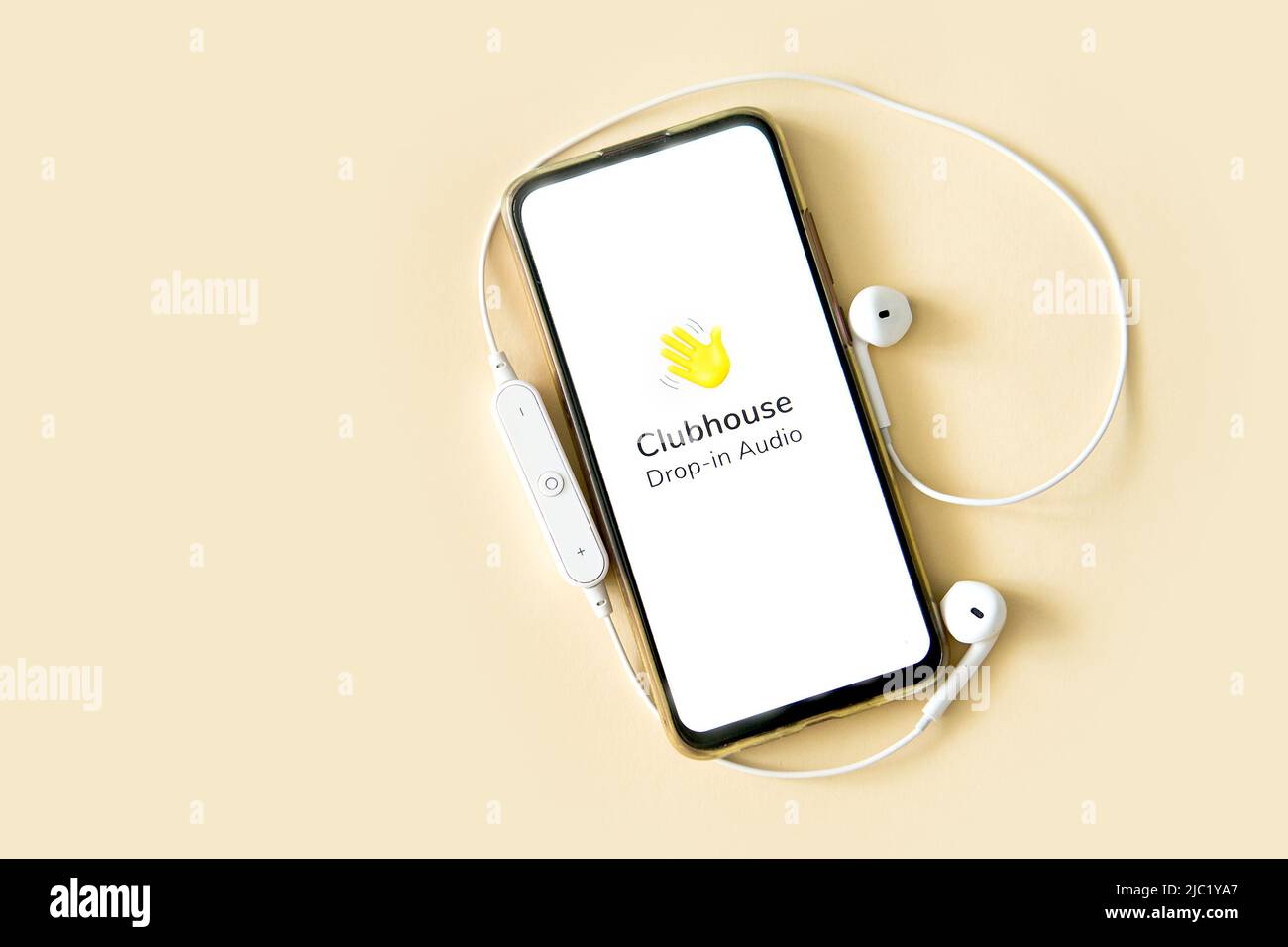 Tver, Russia - 30 gennaio 2021: Clubhouse caduta nella visualizzazione dell'applicazione di chat audio sullo smartphone. Smartphone con cuffie su sfondo beige. Foto Stock