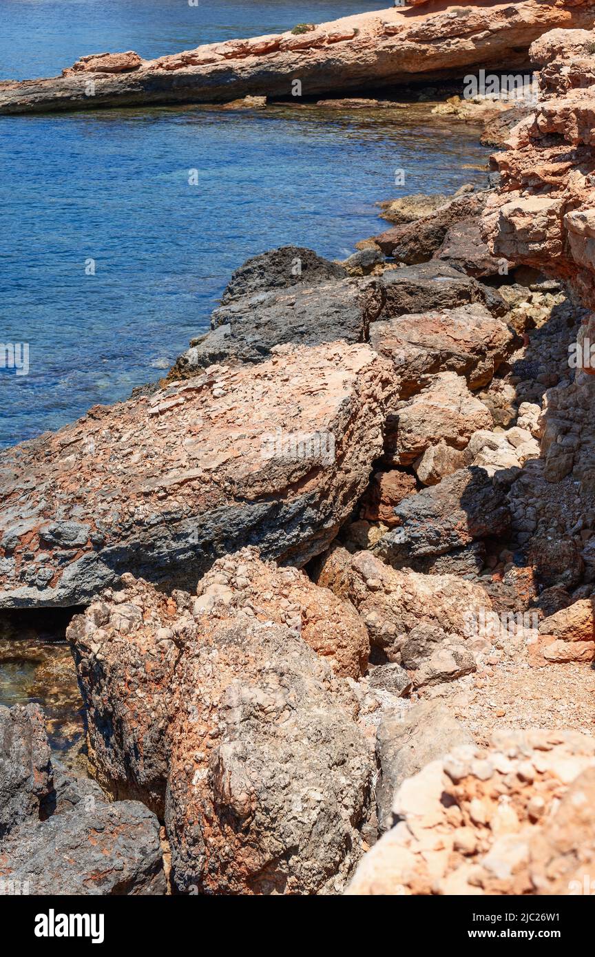 Colpo verticale della costa rocciosa carsica dell'isola e acqua calma e limpida nella baia, Ibiza, Isole Baleari, Spagna Foto Stock
