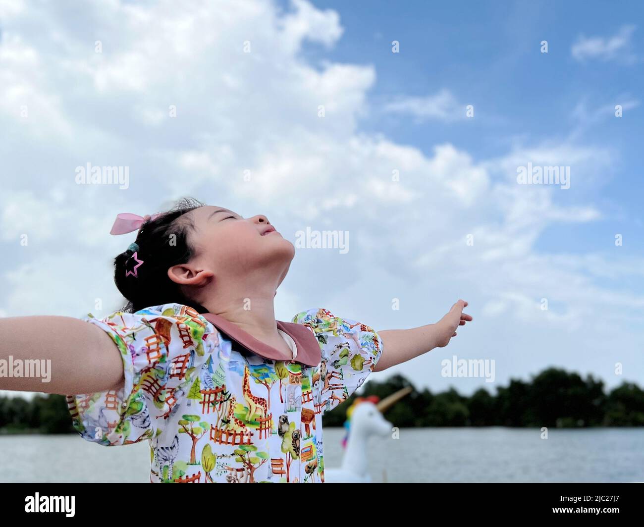 la ragazza piccola carina guarda nel cielo luminoso del giorno per nuove opportunità Foto Stock