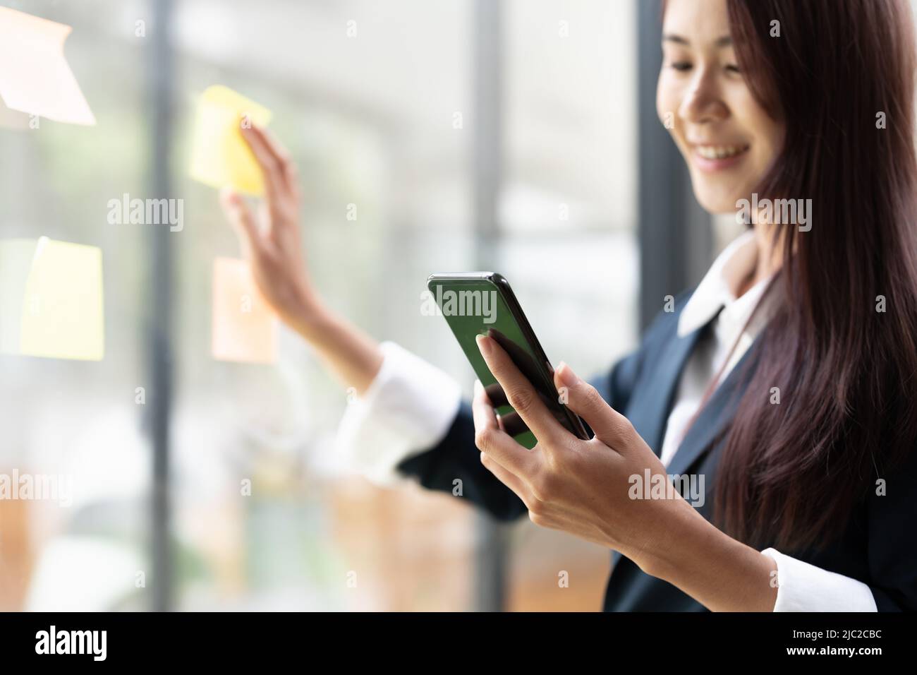 Immagine closeup di una donna d'affari che utilizza il telefono cellulare in ufficio Foto Stock