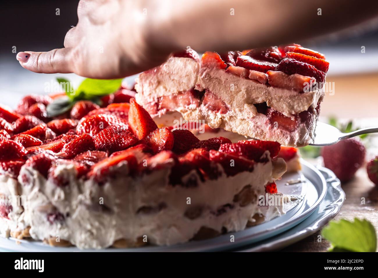 Donna a fette di mano torta di crema di fragole - primo piano. Foto Stock
