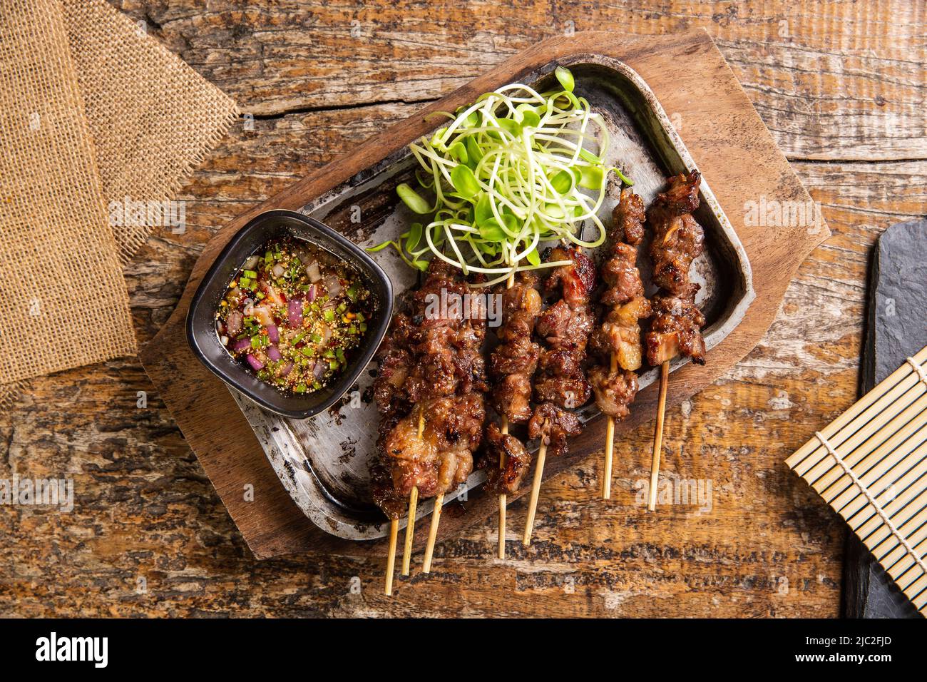 Grigliate in sirloin sulla padella calda decorata con germogli di girasole. Cibo thailandese, vista dall'alto, giorno del cibo mondiale Foto Stock