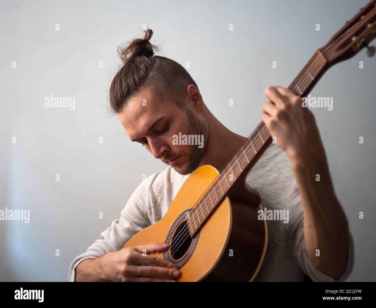 L'uomo bianco suona la chitarra acustica con uno sfondo bianco Foto Stock