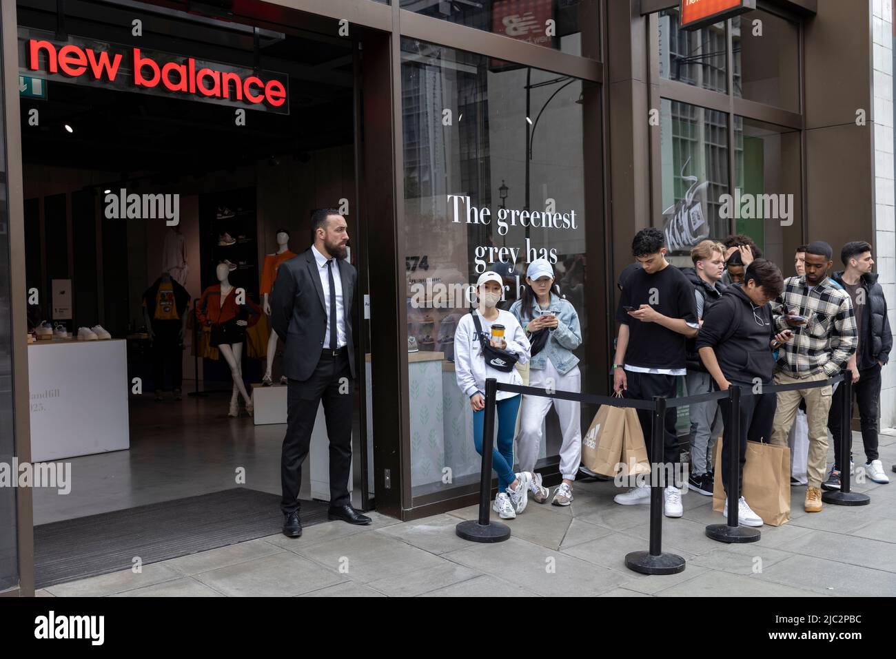 I giovani acquirenti si trovano fuori dal negozio di abbigliamento e scarpe New Balance di Oxford Street, Londra, Regno Unito Foto Stock