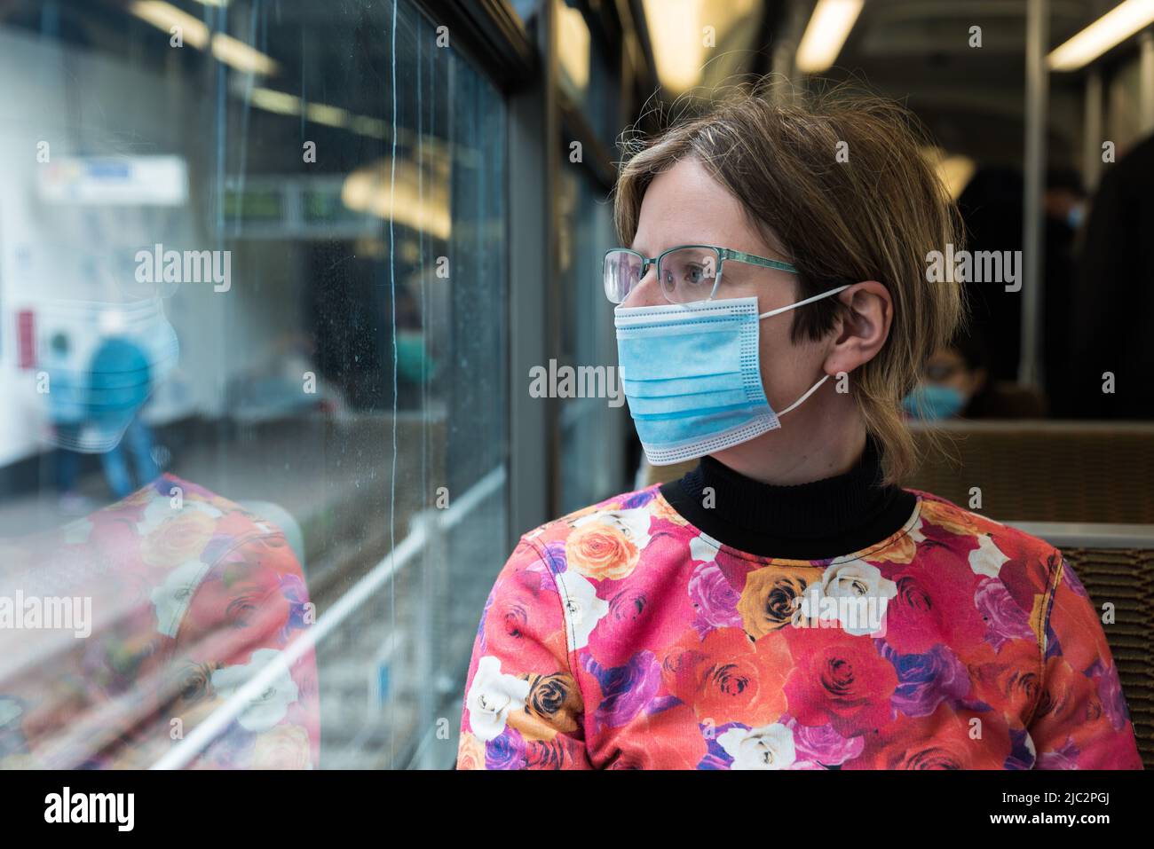 Uccle, Bruxelles Capital Region - Belgio - 05 29 2020 attraente donna di trent'anni che indossa una maschera in bocca seduta sul tram di Bruxelles durante il CO Foto Stock