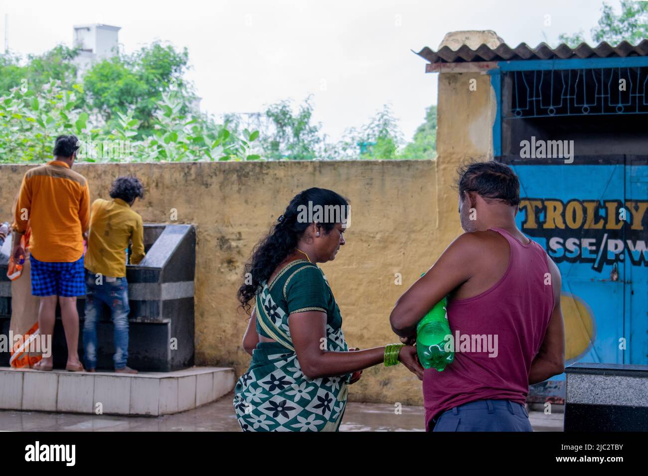 Coppia indiana che raccoglie acqua potabile da tubi in una stazione ferroviaria in India. Foto Stock