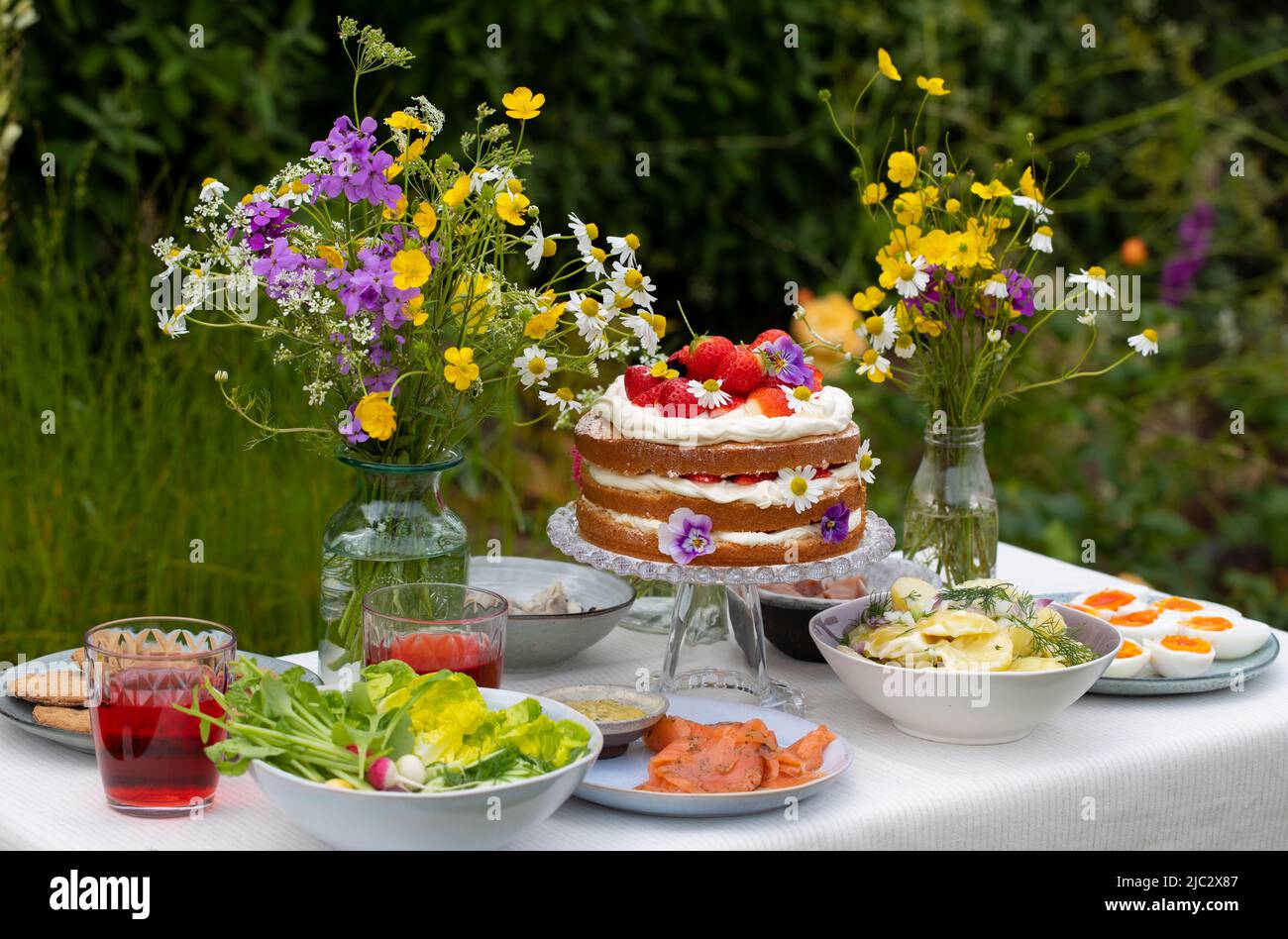 Pasto scandinavo di mezza estate con fragola e torta alla crema, insalata di patate, salmone e uova Foto Stock