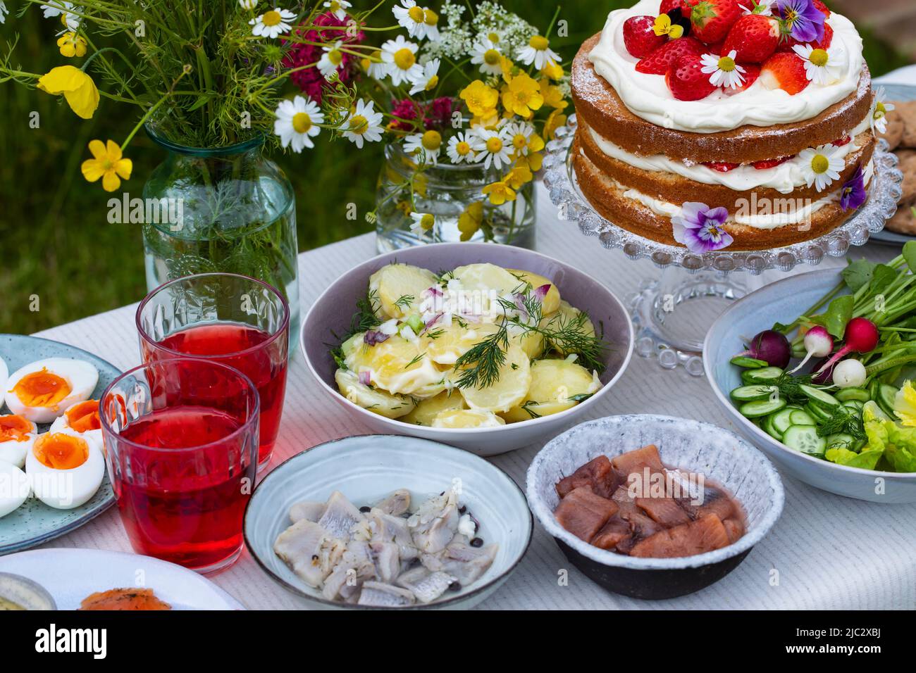 Pasto scandinavo di mezza estate con fragola e torta alla crema, insalata di patate, salmone e uova Foto Stock