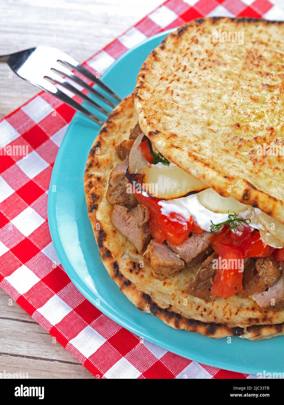 un club sandwich in stile greco fatto con due tradizionali pitas farciti con carne tritata, tzatziki, erbe, cipolla arrosto e pomodoro Foto Stock