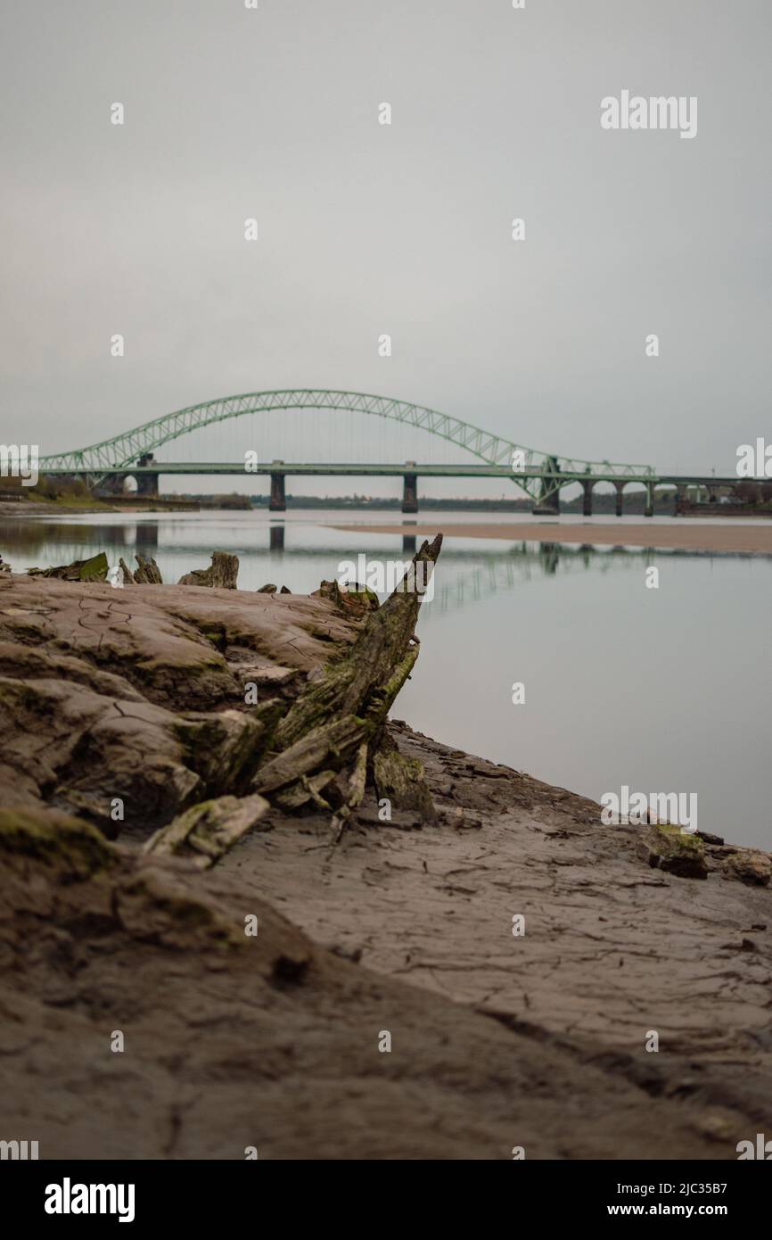 Naufragio sulla spiaggia sabbiosa, Wigg Island, con il Runcorn Bridge / Silver Jubilee Bridge sullo sfondo- Runcorn, Regno Unito. Foto Stock