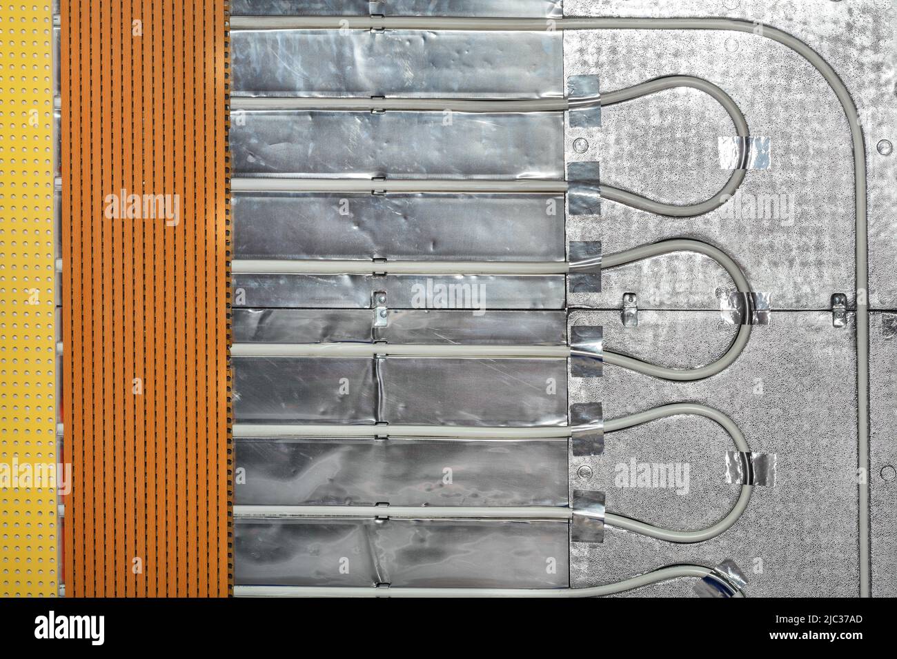 Frammento di tubi di riscaldamento a pavimento con base in foglio e rete metallica protettiva con isolamento termico. Foto Stock