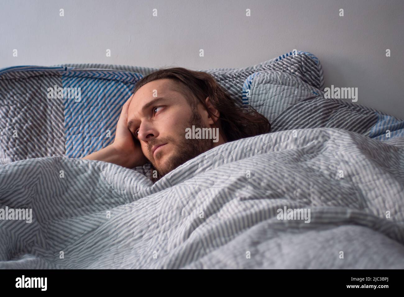 Uomo bianco che dorme all'interno del letto guardando la finestra Foto Stock